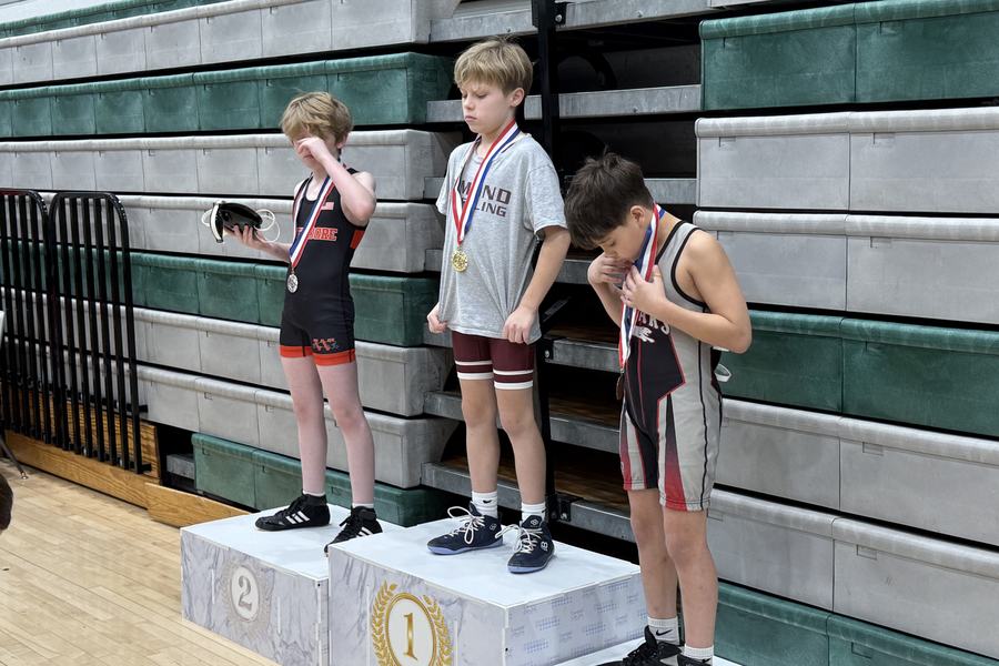 An Edmond wrestler stands on top of the podium